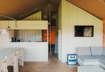 Interior de una cabaña safari con cocina, comedor, sofá y TV en Holiday park De Boshoek, Países Bajos.