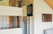 Innenaufnahme des Safari Cottage Zelts im Ferienpark De Boshoek mit Schlafbereich und Fernseher an der Wand.