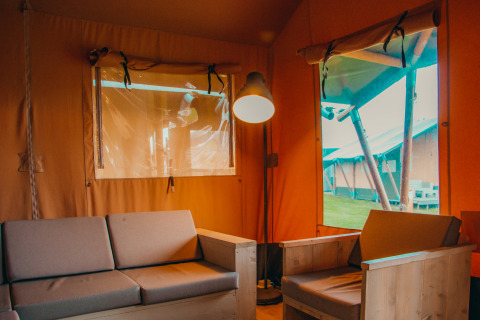 Indre af en safaricottage med sofa og stol, Holiday park De Boshoek, Holland, set indefra et telt.