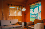 Interieur van een safaritent met bank en stoel bij Holiday park De Boshoek in Nederland, vanuit de tent gezien.