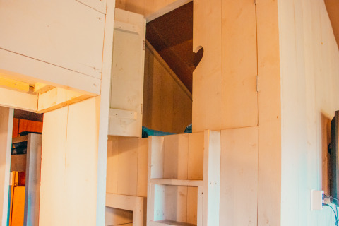 Entrada a un altillo con escaleras y armarios de madera en Safari Cottage en Holiday park De Boshoek, Países Bajos.