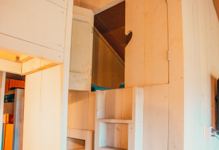 Entrada a un altillo con escaleras y armarios de madera en Safari Cottage en Holiday park De Boshoek, Países Bajos.