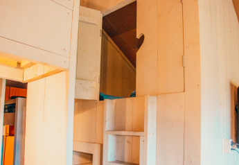 Entrada a un altillo con escaleras y armarios de madera en Safari Cottage en Holiday park De Boshoek, Países Bajos.