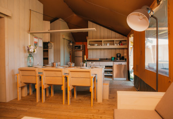 Interno di una tenda safari presso Holiday park De Boshoek nei Paesi Bassi con cucina e zona pranzo.