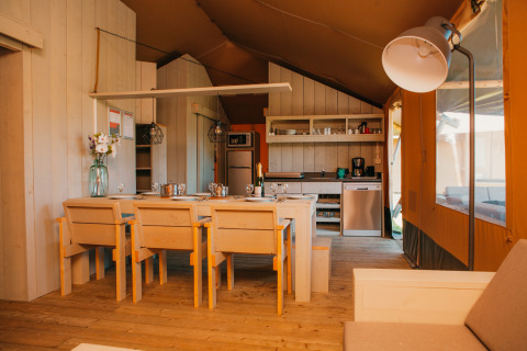 Interior of a safari tent at Holiday park De Boshoek in the Netherlands featuring dining and kitchen area.