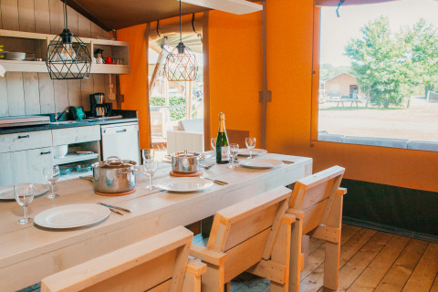 Vue intérieure de la Safari House au Holiday park De Boshoek aux Pays-Bas, avec table en bois et cuisine.