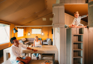 Gezin samen in een Safari House-tent bij vakantiepark De Boshoek in Nederland, sfeervol en gezellig interieur