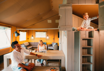 Famiglia che trascorre del tempo nella tenda Safari House al parco vacanze De Boshoek nei Paesi Bassi, interno accogliente