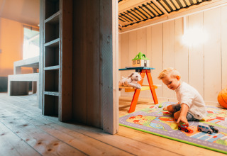 A child plays with toy cars on a colorful mat in the Safari House at Holiday park De Boshoek, Netherlands.