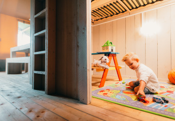 Et barn leger med legetøjsbiler på et farverigt tæppe i Safari House, feriepark De Boshoek, Holland.