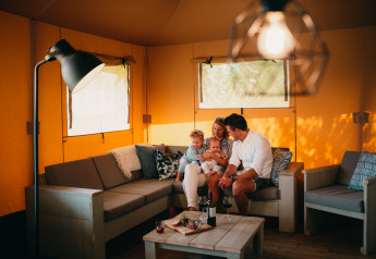 Famiglia che si rilassa in una tenda safari di lusso Safari House al parco De Boshoek nei Paesi Bassi.