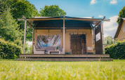 Tienda safari de lujo en Holiday park De Boshoek, Países Bajos, con terraza y rodeada de naturaleza verde.
