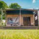 Luxe safaritent lodge op Vakantiepark De Boshoek in Nederland, gelegen tussen groene hagen en bomen.
