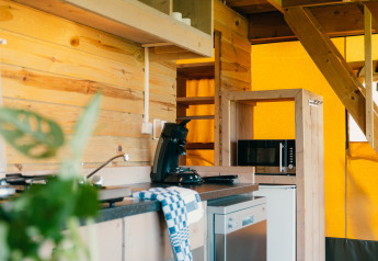 Moderne keukenhoek met houten wanden en apparatuur in een luxe safarilodge op De Boshoek, Nederland.