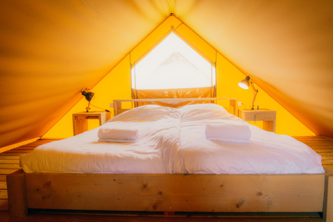Interior de una lujosa tienda safari en Holiday park De Boshoek, Países Bajos, con una gran cama blanca.