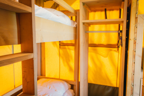 Interno di una tenda safari di lusso con letti a castello e scaffali presso De Boshoek, Paesi Bassi.