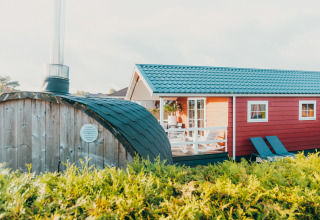 Veluwe lounge med sauna ved Holiday park De Boshoek i Holland, rød hytte og grønne omgivelser.