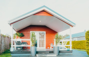 Lodge Veluwe lounge + sauna en Holiday park De Boshoek, Países Bajos, vista frontal con porche y sillas.