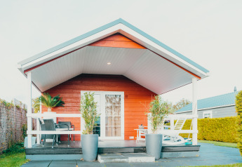 Veluwe lounge + sauna lodge presso Holiday park De Boshoek, Olanda, vista frontale con veranda e sedie.