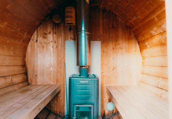 Interno di una sauna in legno con stufa presso Veluwe lounge + sauna a Holiday park De Boshoek, Paesi Bassi.