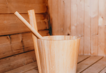 Cubo y cucharón de madera en la sauna de Veluwe lounge + sauna, Holiday park De Boshoek, Países Bajos.