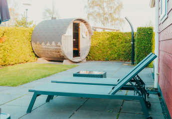 Area lounge esterna con due lettini e una sauna a botte presso Holiday park De Boshoek, Paesi Bassi.