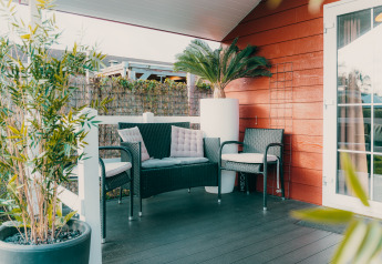 Zona lounge accogliente con sedie in vimini e piante su veranda al Holiday Park De Boshoek, Paesi Bassi.