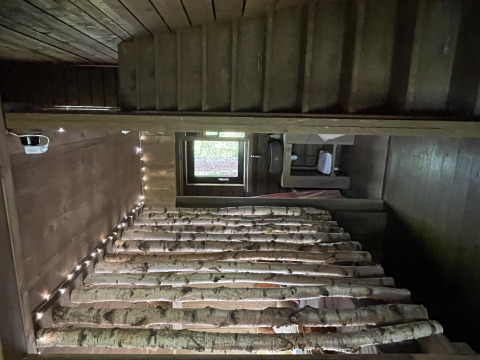 Vue intérieure d'une cabane en bois chaleureuse, lits en bouleau et guirlande lumineuse à Comfort Sweet Wellness.