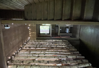 Vue intérieure d'une cabane en bois chaleureuse, lits en bouleau et guirlande lumineuse à Comfort Sweet Wellness.