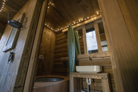 Rustic wooden bathroom with tub, sink, and fairy lights in Comfort Sweet Wellness cabin in Limburg, Belgium.