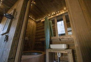 Baño rústico de madera con bañera, lavabo y luces cálidas en Comfort Sweet Wellness, Limburgo, Bélgica.