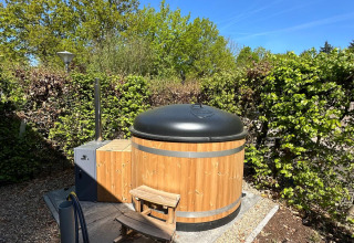 Holz-Whirlpool mit schwarzem Deckel im Tiny Lodge im Veluwepark de Bosgraaf, Niederlande.
