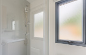 Moderne Dusche mit abgetöntem Fenster im Prestige Cottage auf Camping Seasonova Haliotis, Frankreich.