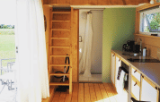 Sfeervol lodge-interieur met slaapzolder, keuken en douche in Het Eilandhuis, 7Huizen aan Zee, Nederland.