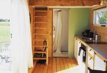 Interior de acogedora cabaña con altillo, cocina y ducha en Het Eilandhuis, 7Huizen aan Zee, Países Bajos.