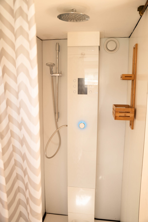 Moderne douche met digitaal bedieningspaneel, regendouche en houten plank bij Het Eilandhuis, 7Huizen aan Zee.