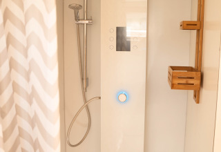Moderne douche met digitaal bedieningspaneel, regendouche en houten plank bij Het Eilandhuis, 7Huizen aan Zee.