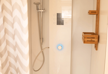 Ducha moderna con panel digital, cabezal tipo lluvia y estante de madera en Het Eilandhuis, 7Huizen aan Zee.
