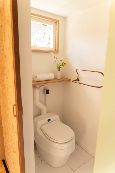 Et lille, lyst badeværelse på Het Eilandhuis i 7Huizen aan Zee, Holland, med vindue og komposttoilet.