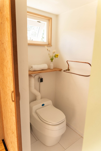 Et lille, lyst badeværelse på Het Eilandhuis i 7Huizen aan Zee, Holland, med vindue og komposttoilet.