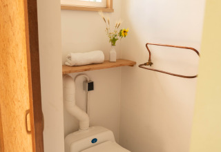 Et lille, lyst badeværelse på Het Eilandhuis i 7Huizen aan Zee, Holland, med vindue og komposttoilet.