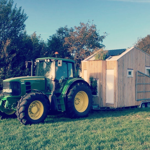 Groene tractor met tiny house van hout en zonnepanelen bij Het Eilandhuis, 7Huizen aan Zee, Nederland.
