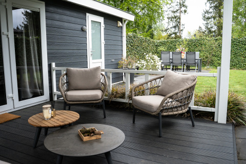 Terraza exterior de Heuvelrug Cottage en De Thijmse Berg, Países Bajos, con sillones modernos y jardín verde.