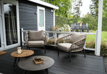 Terrasse der Heuvelrug Cottage im De Thijmse Berg, Niederlande, mit stilvollen Stühlen und Esstisch im Garten.