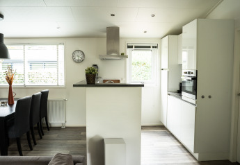 Moderne køkken og spiseområde i Heuvelrug Cottage med store vinduer, lyse vægge og minimalistisk indretning.