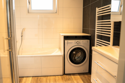 Modernes Bad mit Waschmaschine, Badewanne und Handtuchheizkörper im Heuvelrug Cottage, De Thijmse Berg, Niederlande.