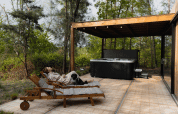 Frau entspannt sich mit Hund auf Liege neben Whirlpool bei Comfort Sweet Wellness, Cosy Cabins, Limburg, Belgien.