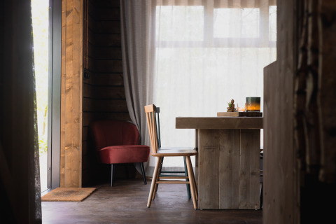 Interno accogliente di una cabina con mobili in legno, sedia rossa e ampie finestre a Limburg, Belgio.