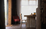 Gezellig cabine-interieur met houten meubels, rode stoel en grote ramen in het bos van Limburg, België.