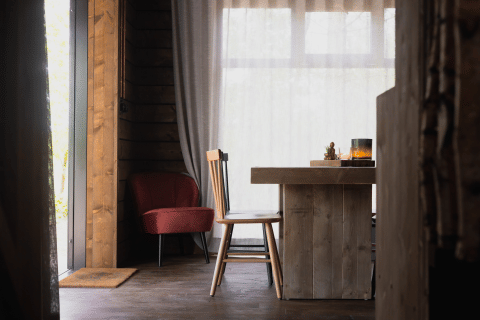 Gemütliches Kabineninterieur mit Holztisch, Stuhl und rotem Sessel im Wald von Limburg, Belgien.